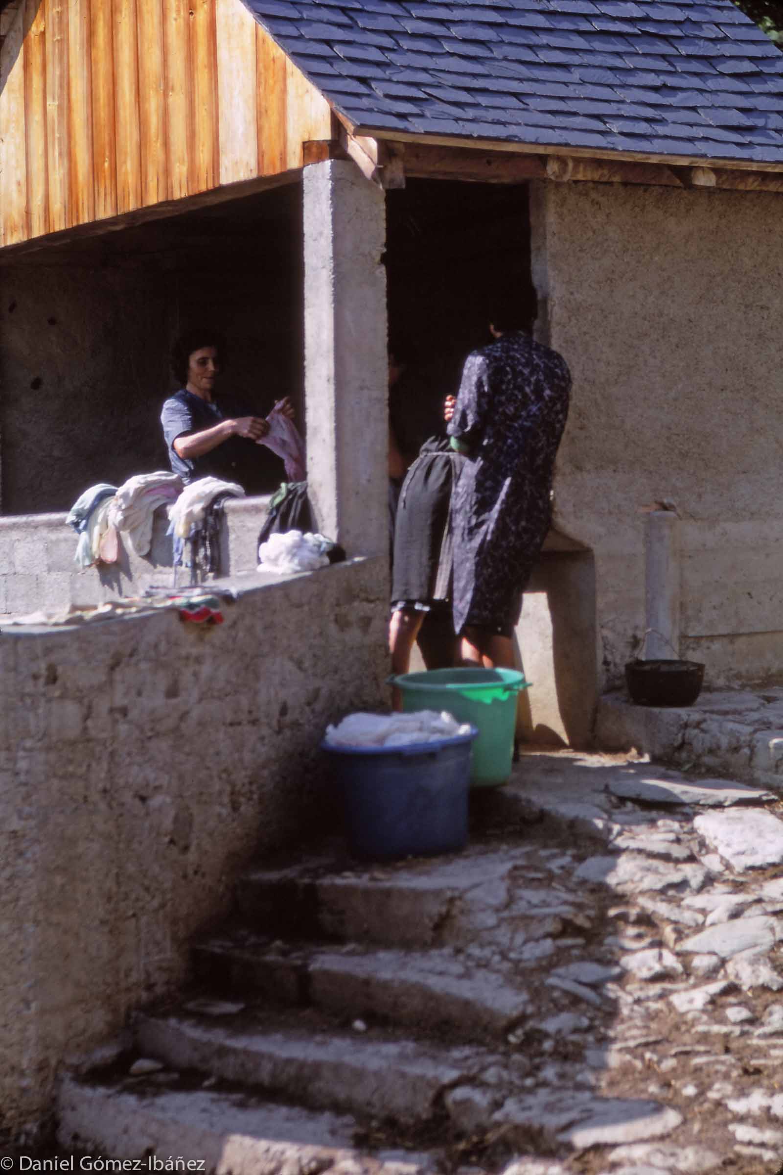 In the 1960s most of Mont's houses lacked running water. Three housewives chat as they do laundry. A mountain spring runs through the wash trough.