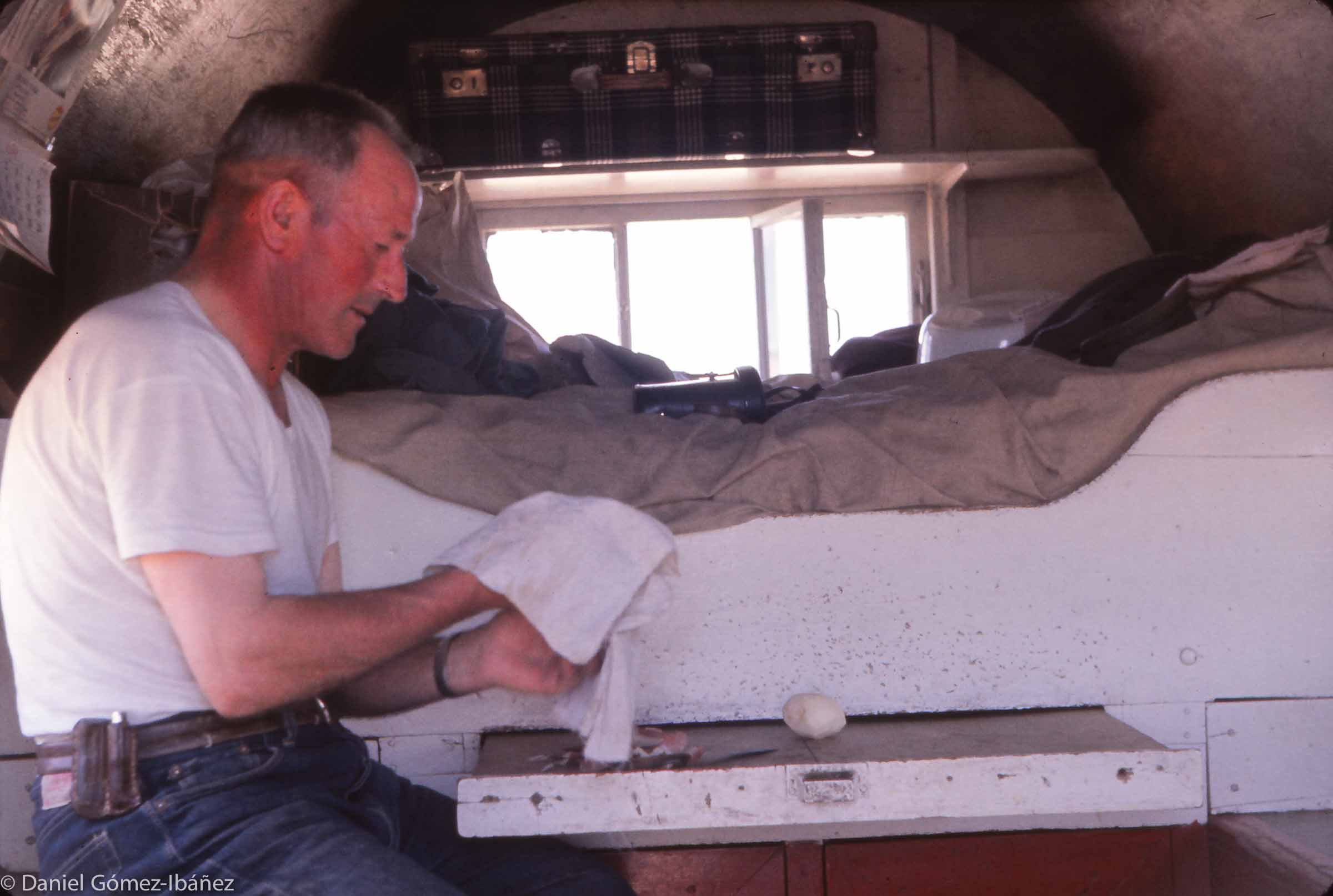 Peeling potatoes for stew, Martin Escurdia sits in front of his camp bed. The suitcase above the window was all he brought when he came from Spain to Wyoming on a three-year contract.